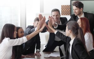A team of businesspeople giving high five while sitting at the desk